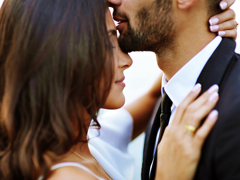 На фото изображены молодой человек и девушкаю Молодой человек нежно целует девушку в лоб